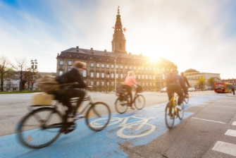 Radfahrer*innen radeln auf dem Radweg an der Straße in einer Stadt.