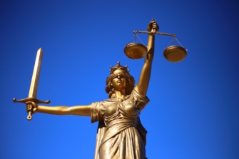 Bronze-Statue von Justitia mit verbundenen Augen, einem Schwer in der einen und einer Waage in der anderen Hand.