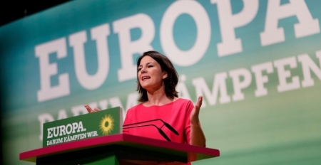 Annalena Baerbock vor einem Podest mit einem Schild. Text: Europa. Darum kämpfen wir. Im Hintergrund ist der Schriftzug erneut zu sehen.